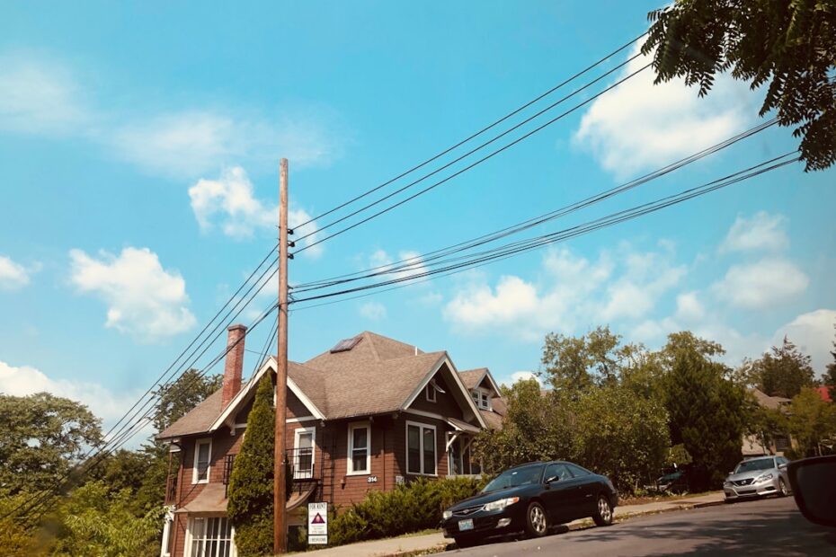 Bright, modern suburban house with a 'For Sale' sign in the manicured front lawn on a sunny day, representing the start of...