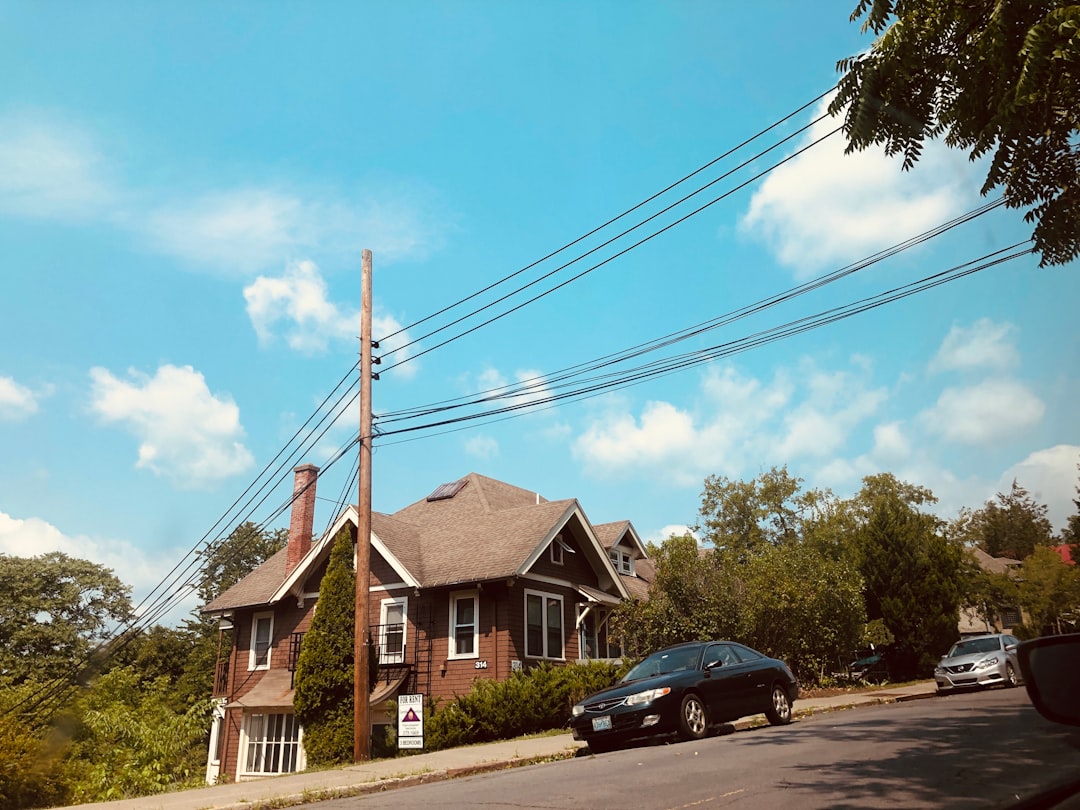 Bright, modern suburban house with a 'For Sale' sign in the manicured front lawn on a sunny day, representing the start of...