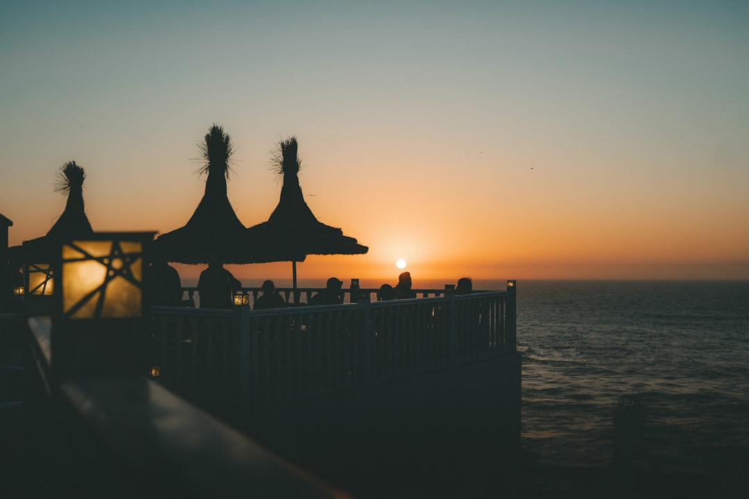 A relaxed couple enjoying a beautiful sunset over the ocean from the balcony of their vacation home in a tropical location like Cabo.