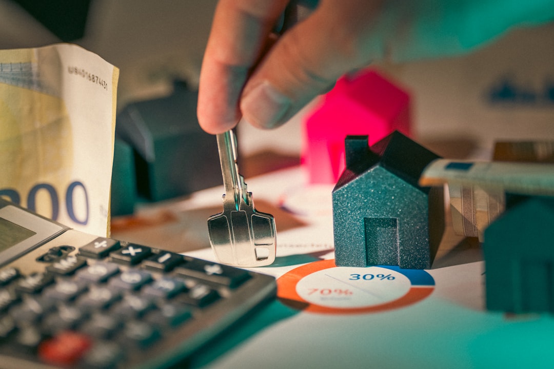A small model of a house sits on a professional desk next to a calculator and financial documents, symbolizing the process of calculating property taxes for a new home.